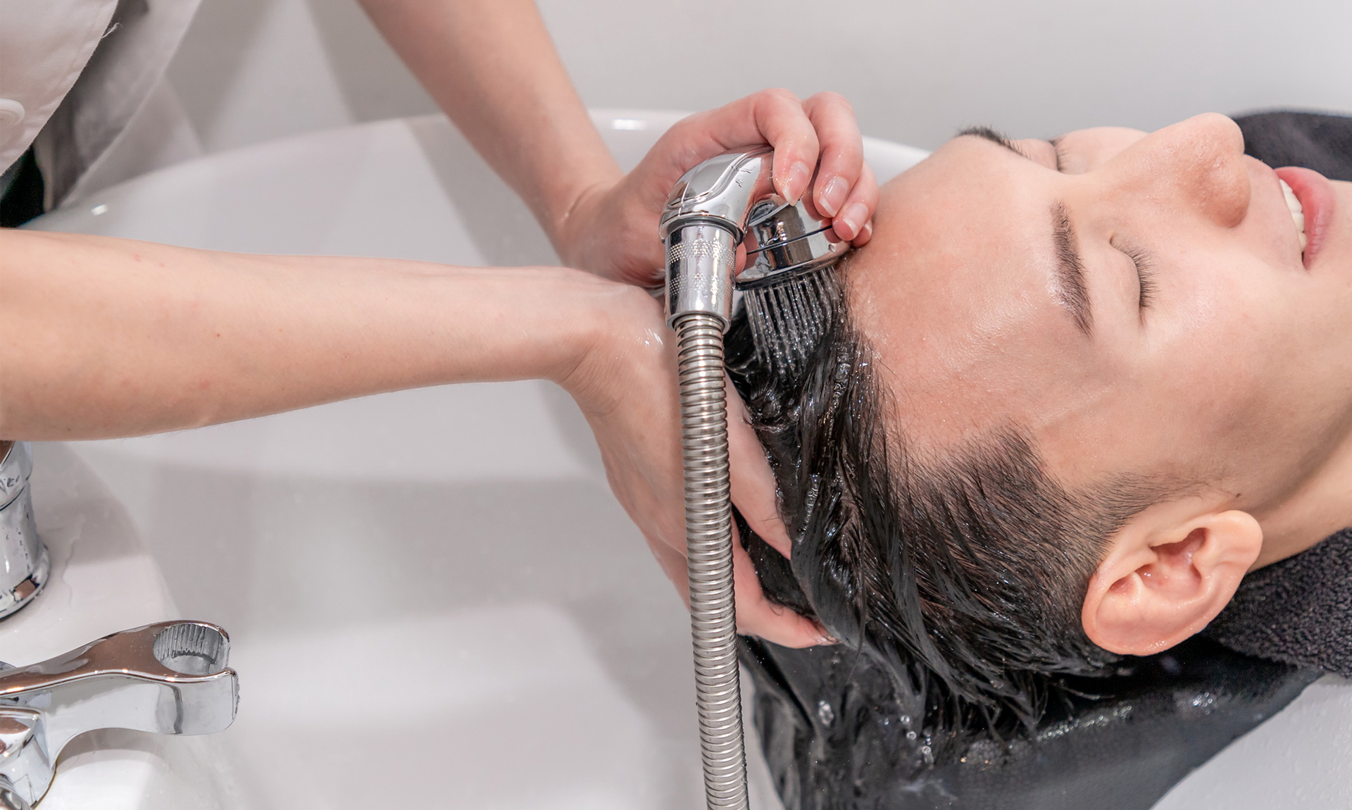 A hair specialist washing a person's hair - Feathair